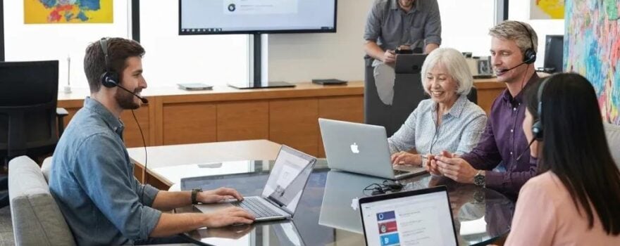 Team collaborating in a modern office using laptops and headsets for Business VoIP communication, emphasizing affordable Utah phone services and enhanced collaboration.